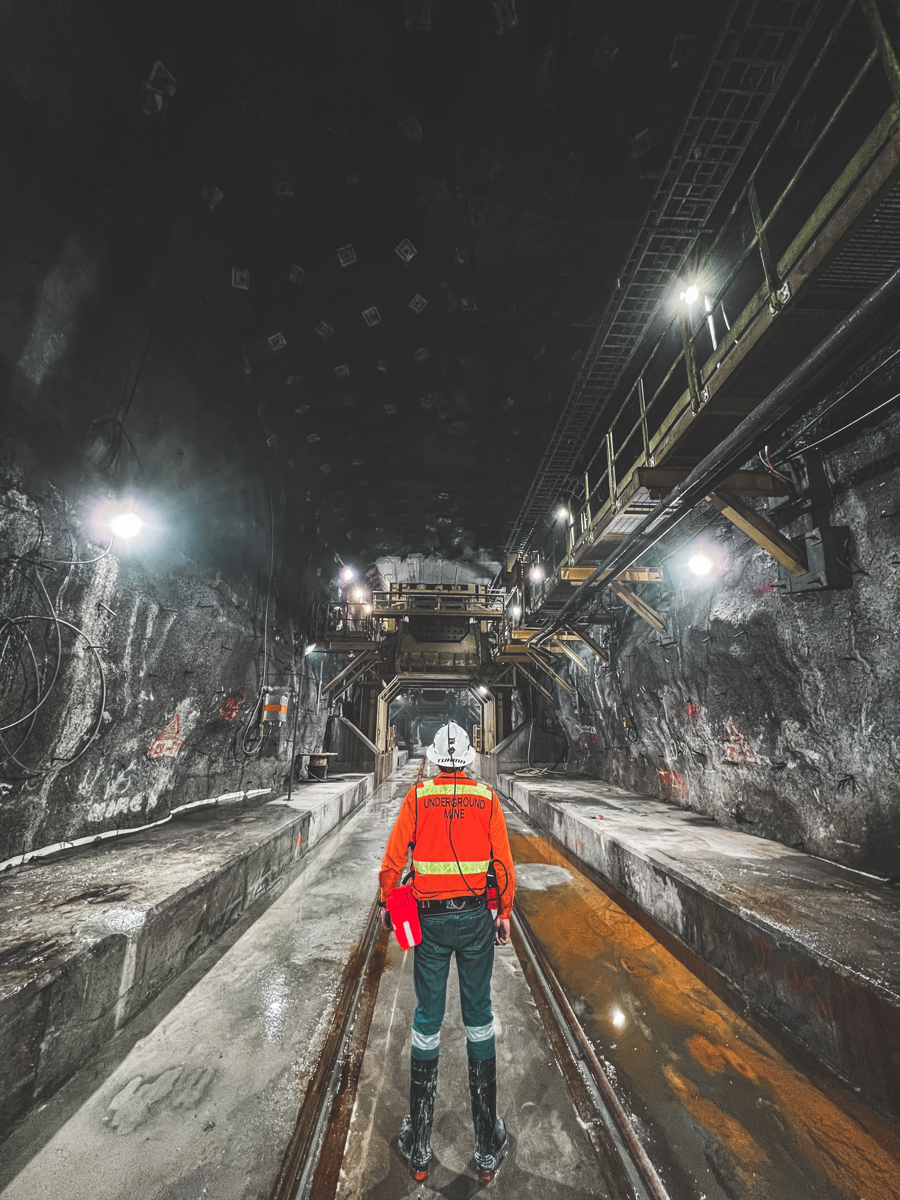 Underground mine infrastructure with a worker standing between rail tracks